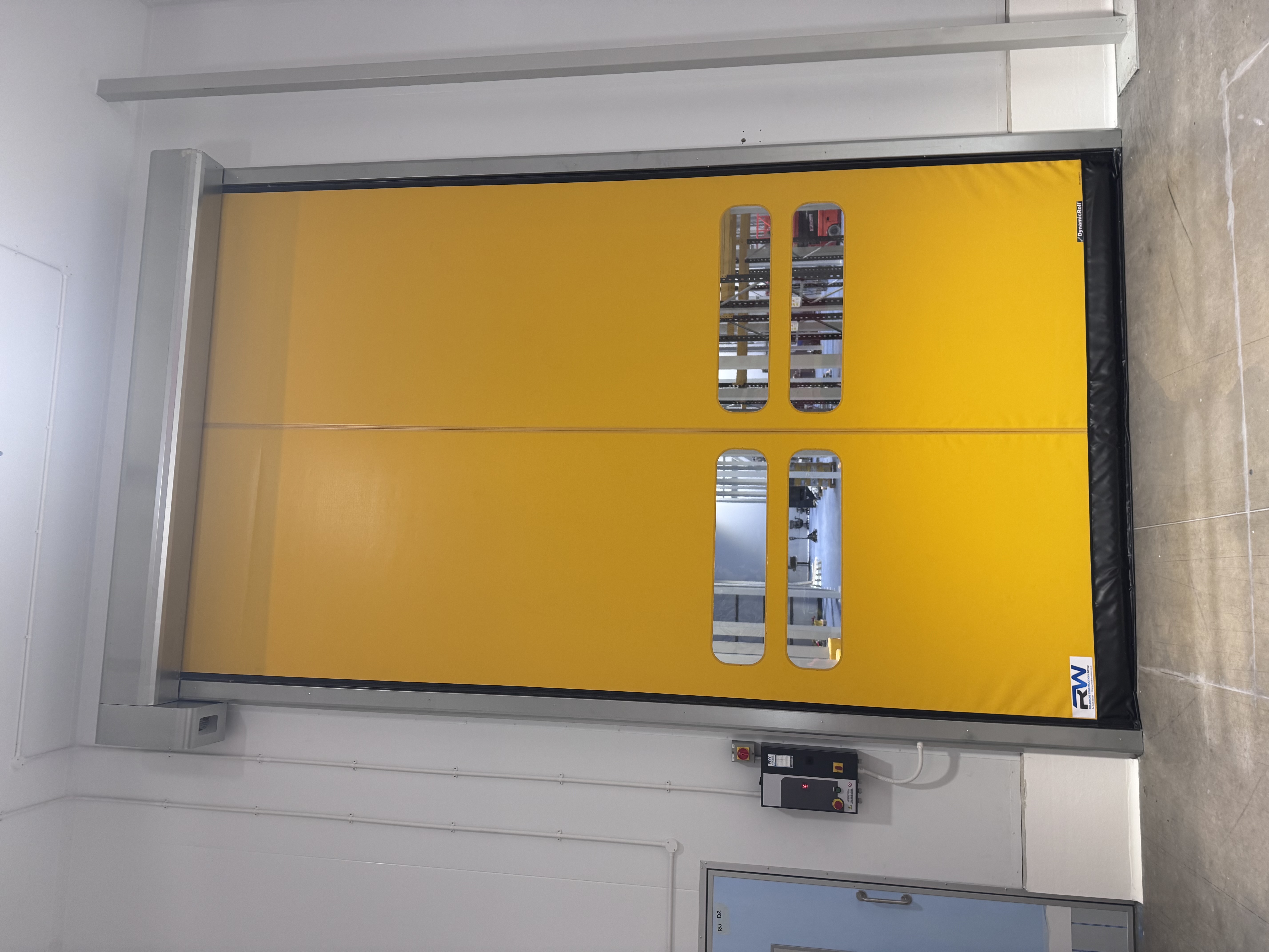 Yellow rapid-roll door with vision windows in coldstore